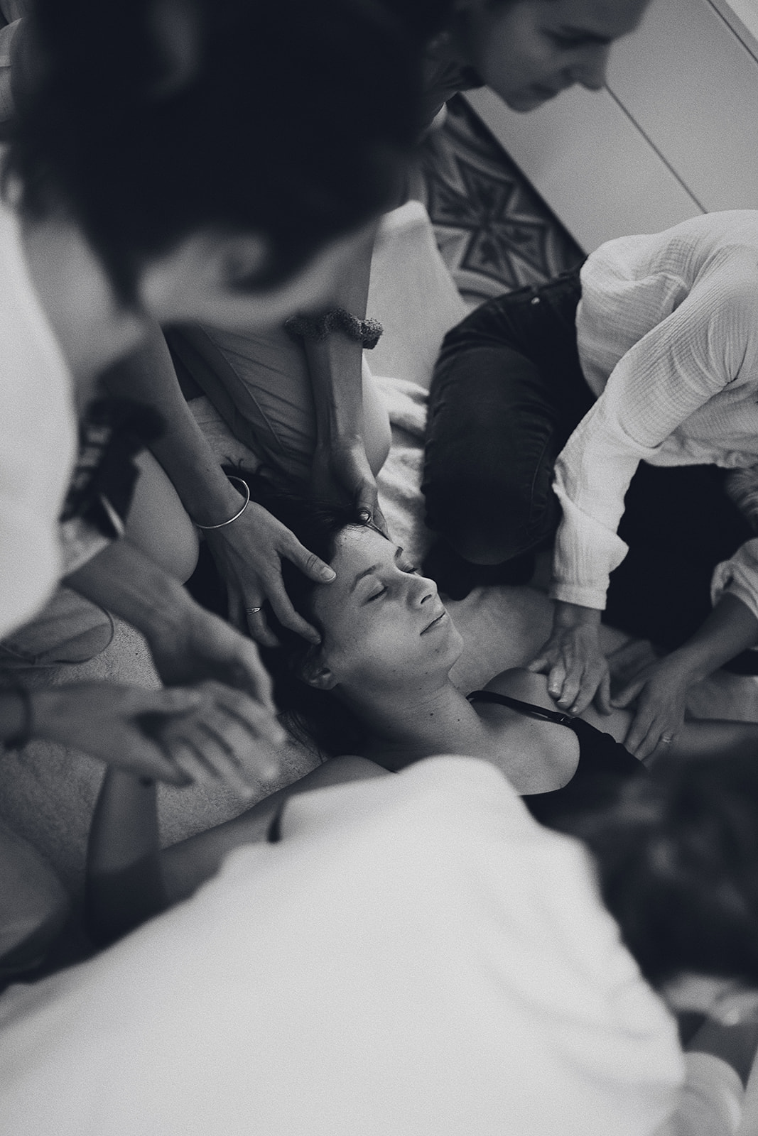 photo d'un célébration de fin de grossesse. une femme enceinte allongée sur le dos, en train de se faire masser par plusieurs autres femmes (on en voit 4 sur la photo). Doula Arles Tarascon